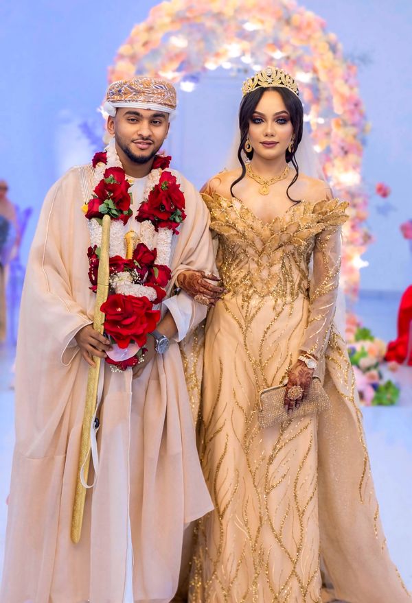 Arab groom in a floral garland beside his bride in gold