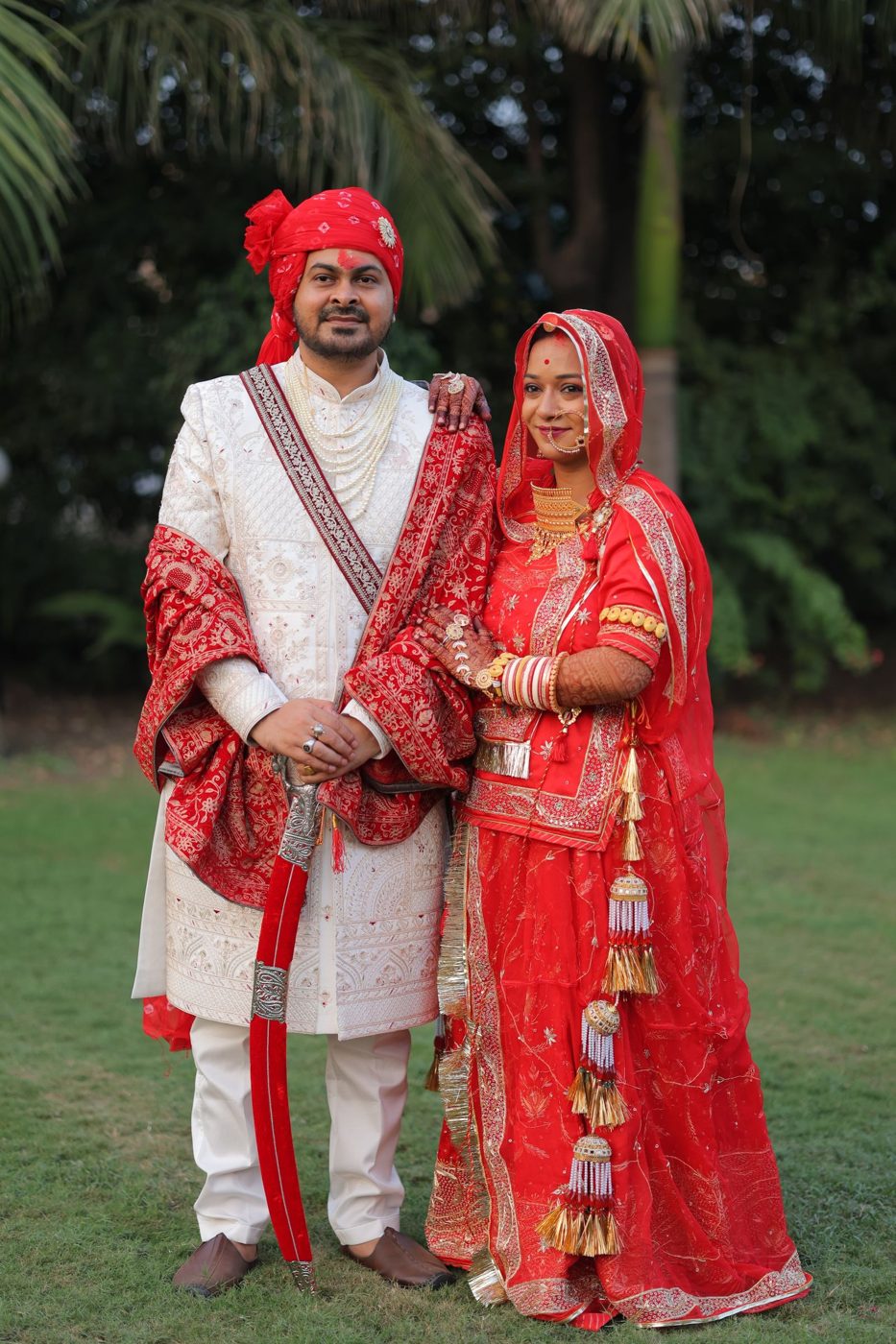 Indian bride and groom in red and ivory wedding attire
