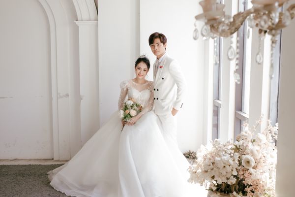 East Asian newlyweds in a bright wedding studio